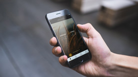 En hand som håller i en mobiltelefon som visar inom- och utomhustempratur. Foto